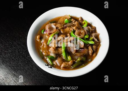 Herzhaftes, gebratenes Rindfleisch mit grüner Paprika und Zwiebeln in Rich Brown Sauce, serviert in einer traditionellen Schüssel für ein schmackhaftes asiatisch inspiriertes Gericht Stockfoto