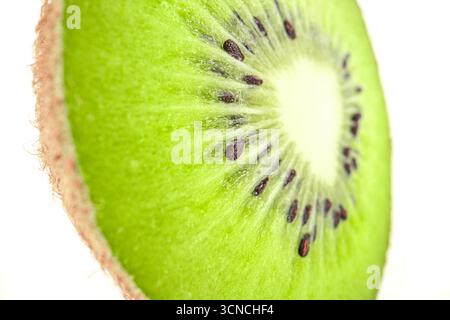 Zwei Kiwis werden in zwei Hälften geschnitten und auf einem weißen Hintergrund platziert. Die Kiwis sind grün und haben schwarze Samen Stockfoto