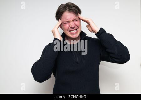 Skandinavischer mittelerwachsener Mann mit Kopfschmerzen im schwarzen Pullover-Porträt vor weißem Studiohintergrund Stockfoto