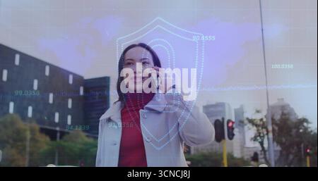 Sprechende Frau auf Smartphone im Mantel, roter Pullover auf dem Bürgersteig, mit digitalem Schild, Ampeln Stockfoto