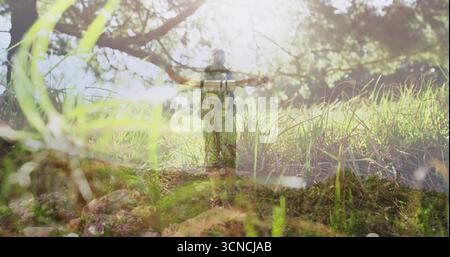 Wanderer durchqueren Waldlichtung in Wanderausrüstung mit Rucksack, Wanderschuhen, Gräsern und Ästen Stockfoto