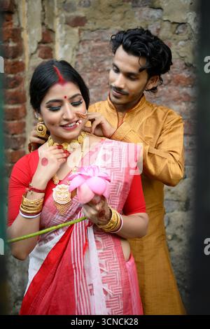 Eine junge indische Frau erhält während eines festlichen Moments eine goldene Halskette von ihrer Geliebten, beide in traditioneller Kleidung gekleidet. Stockfoto