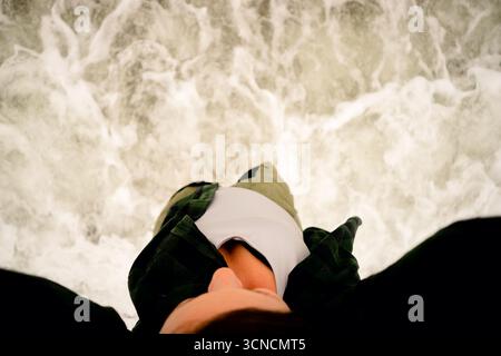Nahaufnahme von Frauenfüßen, die von sanften Meereswellen am Sandstrand gewaschen werden. Perfektes Achtsamkeitskonzept. Stockfoto