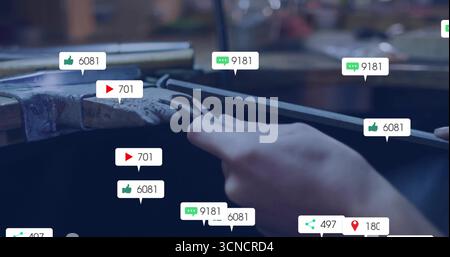 Das Metallstück mit der Hand des Maschinenführers auf dem Schraubstock in der Werkstatt mit schwebenden Social-Media-Ikonen feilen Stockfoto