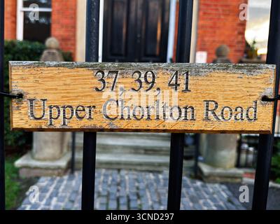 Ein verwittertes hölzernes Straßenschild mit Hausnummern an der Upper Chorlton Road in Manchester, Großbritannien. Stockfoto