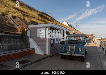 Vintage Land Rover vor dem East Beach Coffee Stop auf der Promenade in Sheringham an der Küste von Norfolk Stockfoto