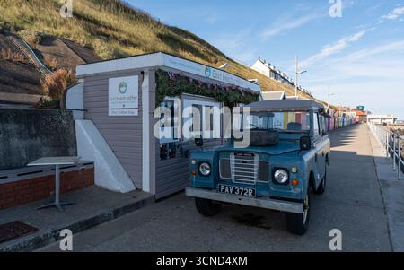 Vintage Land Rover vor dem East Beach Coffee Stop auf der Promenade in Sheringham an der Küste von Norfolk Stockfoto