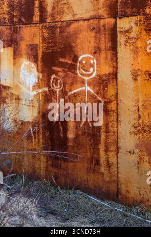 Glückliche Familie mit einem Kind in weiß auf rostiger Garagenwand in Petropavlovsk-Kamtschatski Stadt im Frühling, Region Kamtschatka, Russland Stockfoto
