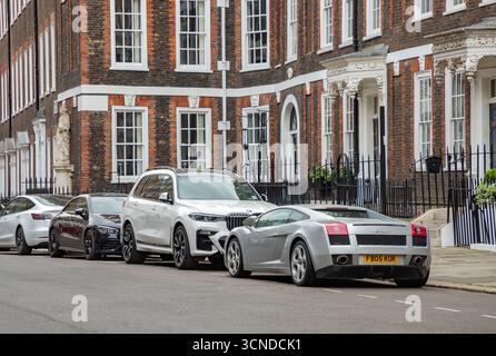Ein Bild von einer Reihe lauter Autos, die vor viktorianischen Häusern in London geparkt sind. Stockfoto