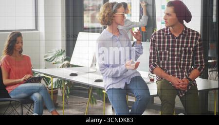 Zusammenarbeit mit vier Kollegen, die Konstruktionen am Arbeitsplatz auf einem Tablet prüfen, mit Whiteboard-Haftnotizen Stockfoto