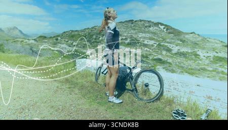 Radfahrer im Trikot halten und auf dem Küstenweg mit Rennradhelm, Sonnenbrille und gepunktetem Überzug beobachten Stockfoto