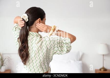 Wunderschöne Frau mit Pferdeschwanz und Scrunchies im Schlafzimmer, Blick nach hinten Stockfoto