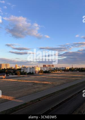 Sonnenuntergang über der Stadt, wunderschöne goldene Strahlen der untergehenden Sonne über der Rennstrecke Stockfoto