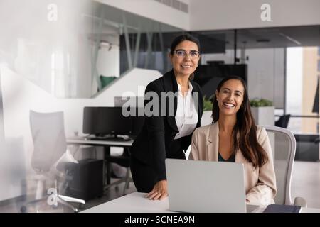 Zwei glückliche, vielfältige Geschäftsfrauen, die sich für ein Firmenporträt ausgeben Stockfoto