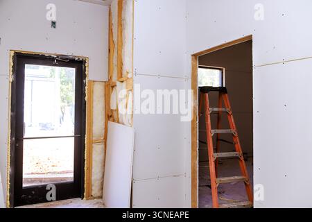Trockenbauwände werden in einem im Bau befindlichen Raum mit Leiter in der Nähe installiert Stockfoto