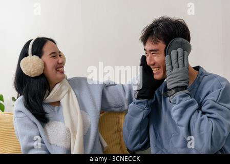 Glückliches Paar genießt gemütliche Wohnung am Wintertag Leute, die drinnen lachen und warme Kleidung tragen wie Stockfoto