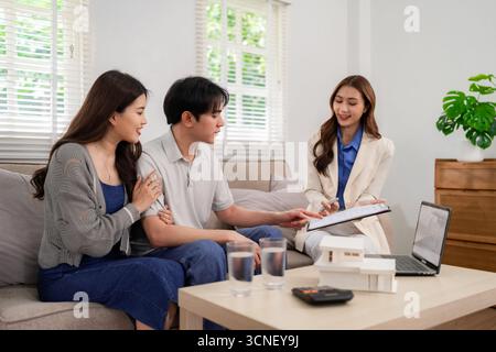 Professionelle asiatische Immobilienmakler bietet fachkundige Beratung junges Paar über Immobilienkauf Investitionspläne Home gemütliche Atmosphäre Stockfoto