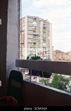 Blick von einer Gebäudeterrasse auf umliegende Wohnblocks, eingerahmt von einem dicken Metallgeländer, aufgenommen in einer nostalgischen Analogfilm-Ästhetik. Stockfoto