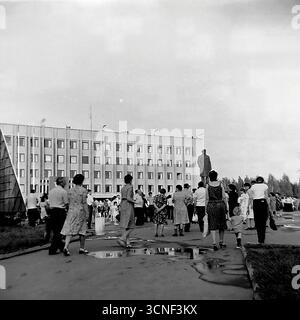 Bewohner und Familien mit Kindern spazieren während des Stadtfestes in Sloviansk, UdSSR, am 6. September 1985 durch den zentralen Platz der Oktoberrevolution (heute Soborna-Platz) in der Nähe des Lenin-Denkmals. Dieses authentische Schwarzweiß-Reportage-Foto fängt die lebhafte Atmosphäre eines öffentlichen Festivals und einer Massenveranstaltung ein, bei der die Menschen trotz der Pfützen eines früheren Regens gemeinsam den Urlaub genießen und eine typische Szene des bürgerlichen Lebens in der Sowjetzeit darstellen Stockfoto