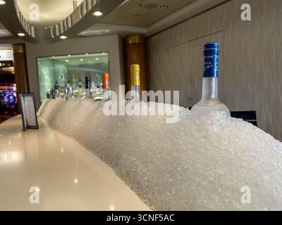 Ein klassischer Martini serviert in der Martini Bar mit beleuchteten Spirituosenflaschen und gehobenem Bar-Ambiente an Bord eines luxuriösen Kreuzfahrtschiffes. Stockfoto