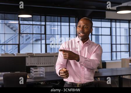 afroamerikanischer Mann mit Gesten bei der Präsentation des Projekts im Büro mit Drehstühlen Stockfoto