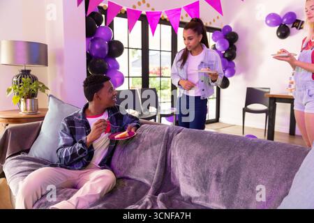 Verschiedene Teenager-Freunde treffen sich zu Hause mit Ballons und Fahnen, mit Kuchen und Kopierraum Stockfoto