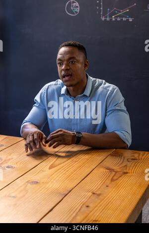 afroamerikaner präsentiert Tafelkarten am Tisch im Klassenzimmer mit Armbanduhr Stockfoto