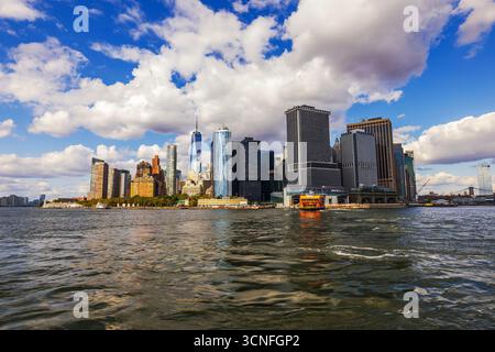 Orange Staten Island Fähre auf dem Wasser vor dem Hintergrund der Wolkenkratzer in Lower Manhattan und des One World Trade Center. New York. USA. Stockfoto