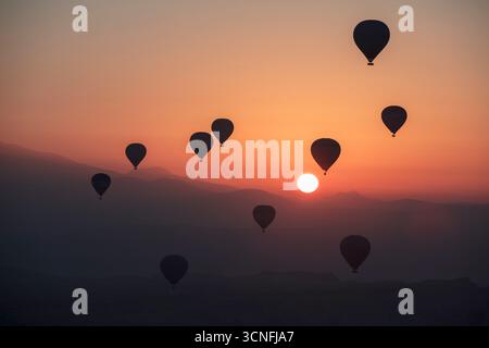 Farbenfrohe Heißluftballons bei Sonnenaufgang über Kappadokien in der Türkei, magischer Ballonflug über dramatischen Tälern und Felsformationen Stockfoto