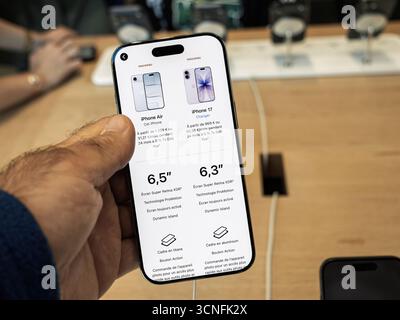 Paris, Frankreich - 19. September 2025: Eine Hand hält ein iPhone und zeigt einen Vergleichsbildschirm zwischen dem iPhone Air und dem iPhone 17, wobei Design, Display und Display hervorgehoben werden Stockfoto