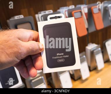 Paris, Frankreich - 19. September 2025: Nahaufnahme der Hand mit der neuen Apple iPhone FineWoven Wallet MagSafe Zubehörverpackung im Apple Store mit Regalen Stockfoto