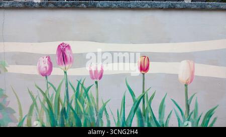 Malte ein Frühlingstulpen-Wandgemälde auf einer weichen gestreiften Wand mit grünem Gras im Vordergrund Stockfoto