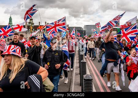 Während der Unite the Kingdom Rallye in London, Großbritannien, marschieren die Menschen über die Westminster Bridge und schwenken das Kreuz der St George und die Union Flags Stockfoto