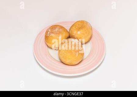 Goldene und knusprige Krapfen mit Puderzucker und gemahlenem Zimt, frisch zubereitet und in einem rustikalen Korb angeordnet. Stockfoto