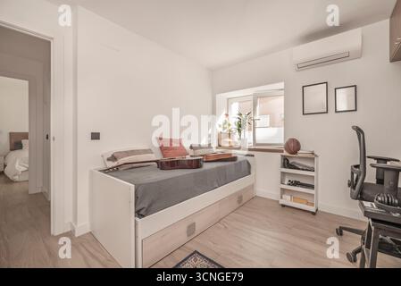 Teenagerzimmer mit schwarzem Metallbett, einem Industrietisch-Schreibtisch und einem Spielesessel mit Lendenwirbelstütze Stockfoto