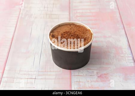 Belgisches Schokoladeneis in einer Wanne mit weißen Schokoladenchips, einem zerbröckelten Keks und einer roten Kirsche darauf, perfekt verarbeitet Stockfoto