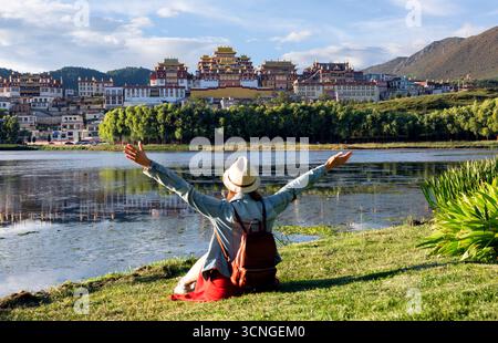 Junge asiatische Frau, die vor dem Songzanlin Kloster in China sitzt, eine berühmte Touristenattraktion in Asien für Sommerreisen. Stockfoto