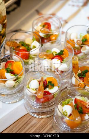 Mini-Salate in Gläsern mit Tomaten, Ei und Kräutern. Elegantes Servieren auf festlichem Tisch Stockfoto