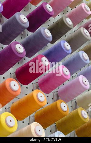 Viele Garnspulen in verschiedenen Farben, Nahaufnahme, abstrakter Textilindustrie Hintergrund Stockfoto