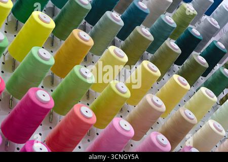 Viele Garnspulen in verschiedenen Farben, Nahaufnahme, abstrakter Textilindustrie Hintergrund Stockfoto