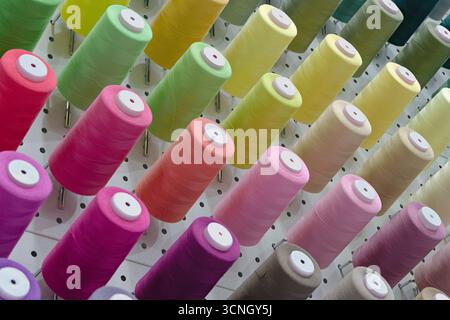 Viele Garnspulen in verschiedenen Farben, Nahaufnahme, abstrakter Textilindustrie Hintergrund Stockfoto