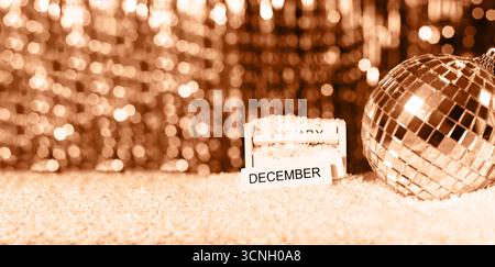 Discokugel aus Silberglas. Neujahrshintergrund mit verschwommenem Bokeh, die Inschrift in englischer Sprache auf dem Holzblock Dezember. Selektive Fokussierung und Sal Stockfoto