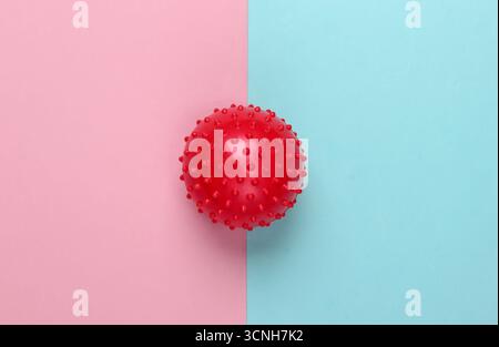 Rote Massagekugel auf rosa blauem Pastellhintergrund. Minimalismus. Gesundheit, Fitnesskonzept. Stockfoto