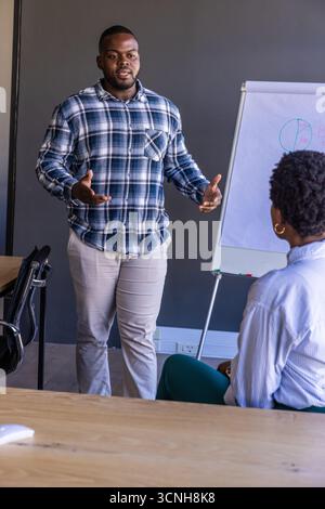 afroamerikanische Kollegen präsentieren Tortendiagramm auf Stativstaffelei bei Bürositzung Stockfoto