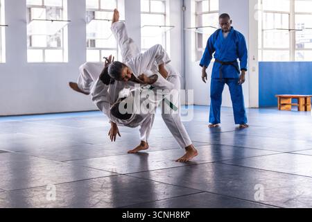 Verschiedene Übungswürfe in weiß, blau auf Dojo-Matten in der Nähe von Fenstern Stockfoto