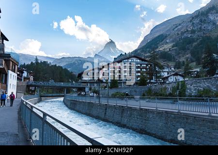 Stadt Zermatt mit dem Matterhorn im Hintergrund, Touristenhütten, Hotels und dem Fluss Matter Vispa, der durch das Zentrum fließt Stockfoto