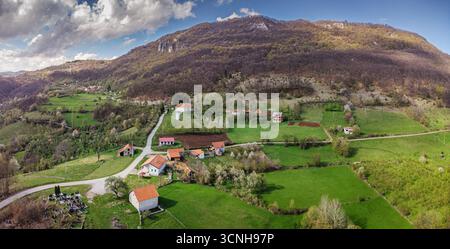 Atemberaubendes Luftpanorama, das das Wesen des ländlichen Lebens mit verstreuten Häusern, grünen Wiesen und einem malerischen Tal in Osteuropa einfängt Stockfoto