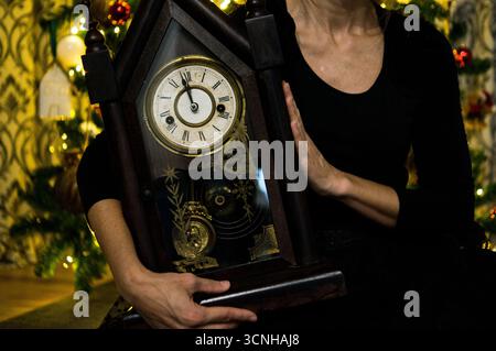 Elegante Frau mit einer Vintage-Uhr vor einem Weihnachtsbaum. Silvesterkonzept. Stockfoto
