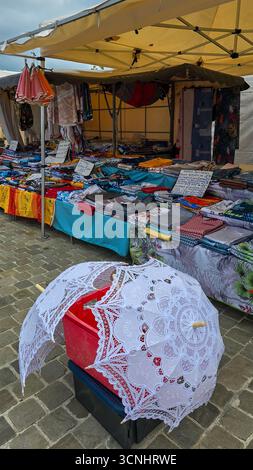 Zwei offene Sonnenschirme mit weißer Spitze auf dem Bürgersteig, auf dem Straßenmarkt. Juni 2025. Soulac-sur-Mer, Medoc, Aquitaine, Frankreich. Stockfoto