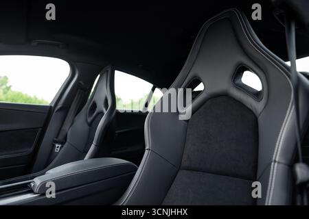 Innenraum der Sportlimousine mit Schaufelsitzen. Vordere Reihe von Autositzen im Fokus und dunkler Innenraum im Hintergrund. Stockfoto